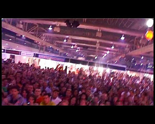 Two girls pleasing a guy in front of an audience