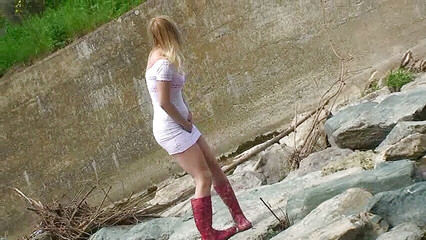 Blonde pissing outside in a river