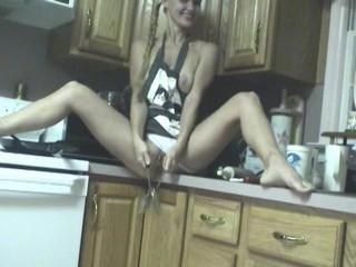 Slutty chick pokes her cunt with kitchen utensils on counter